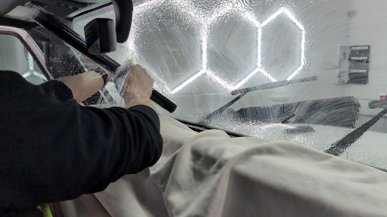 Hands laying ceramic film on a windshield from inside the cabin at Taggart Films