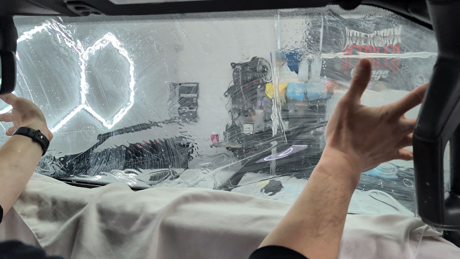 Hands positioning ceramic film on the rear glass from inside the vehicle at Taggart Films