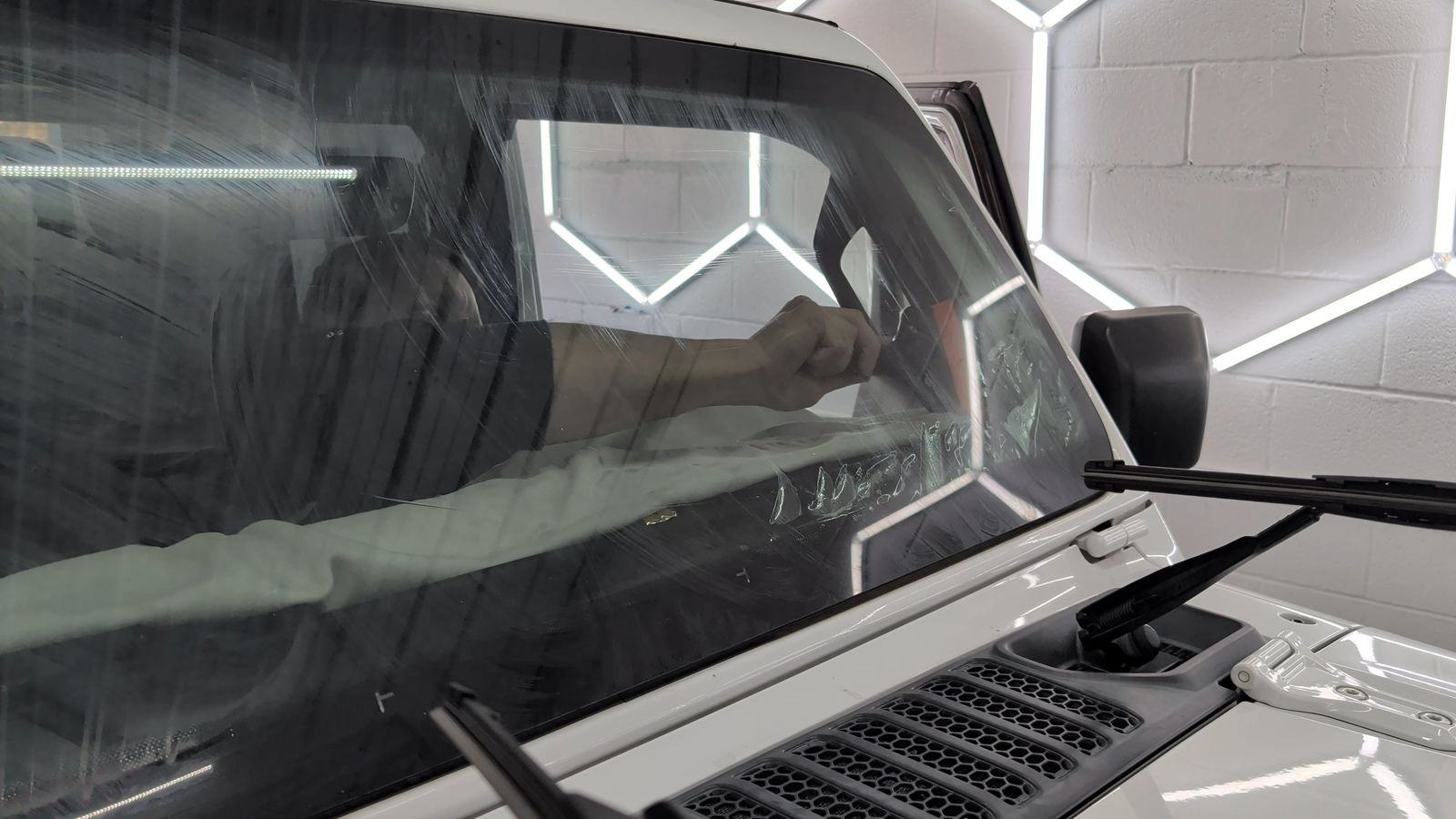 Hand working ceramic film onto the windshield of a white Jeep at Taggart Films