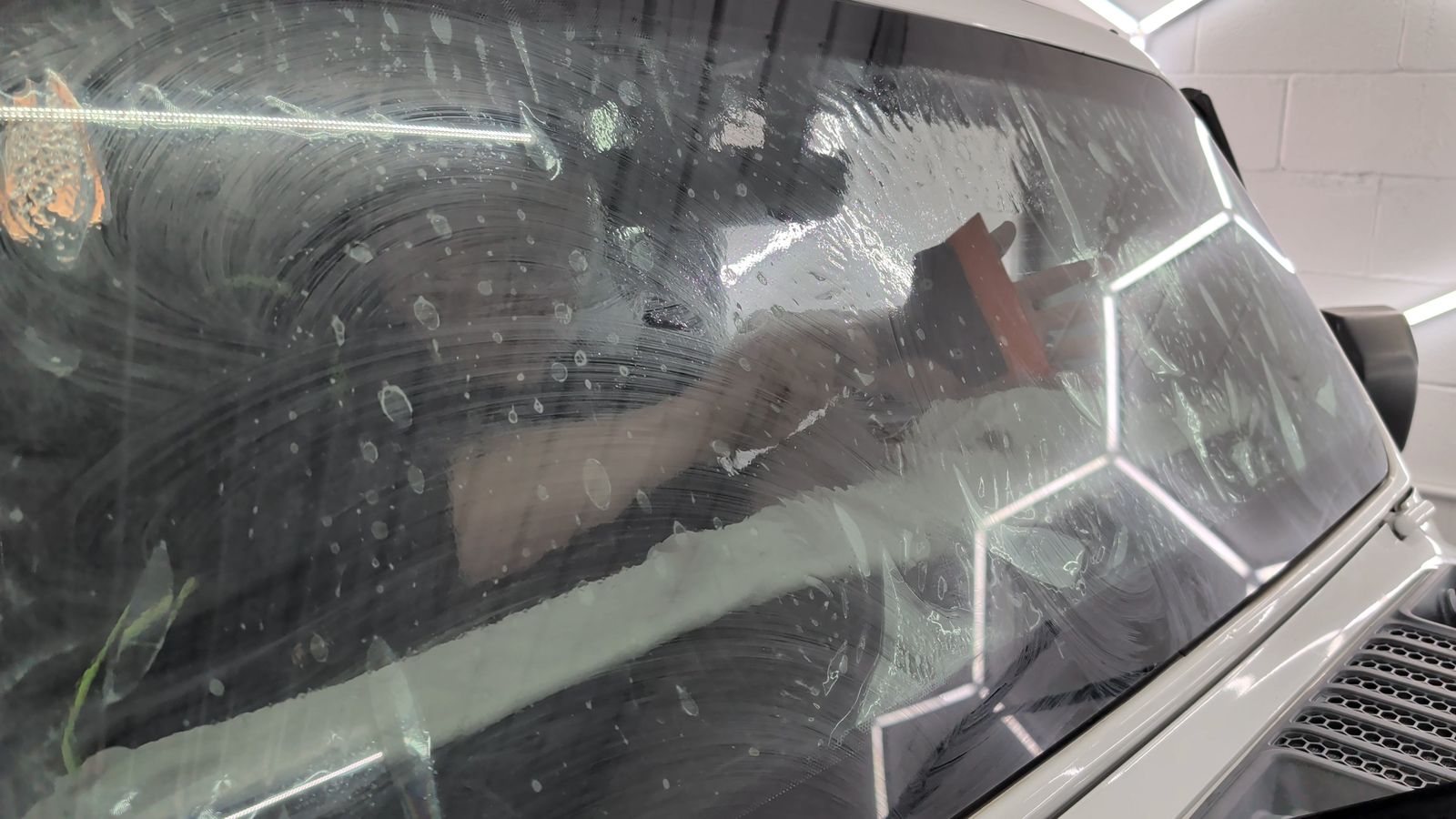 Soapy windshield being squeegeed during a ceramic tint install at Taggart Films